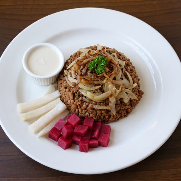 Mujadara with caramelized onions, parsley, a side of tahini sauce, white pickles, and pink pickled turnips.